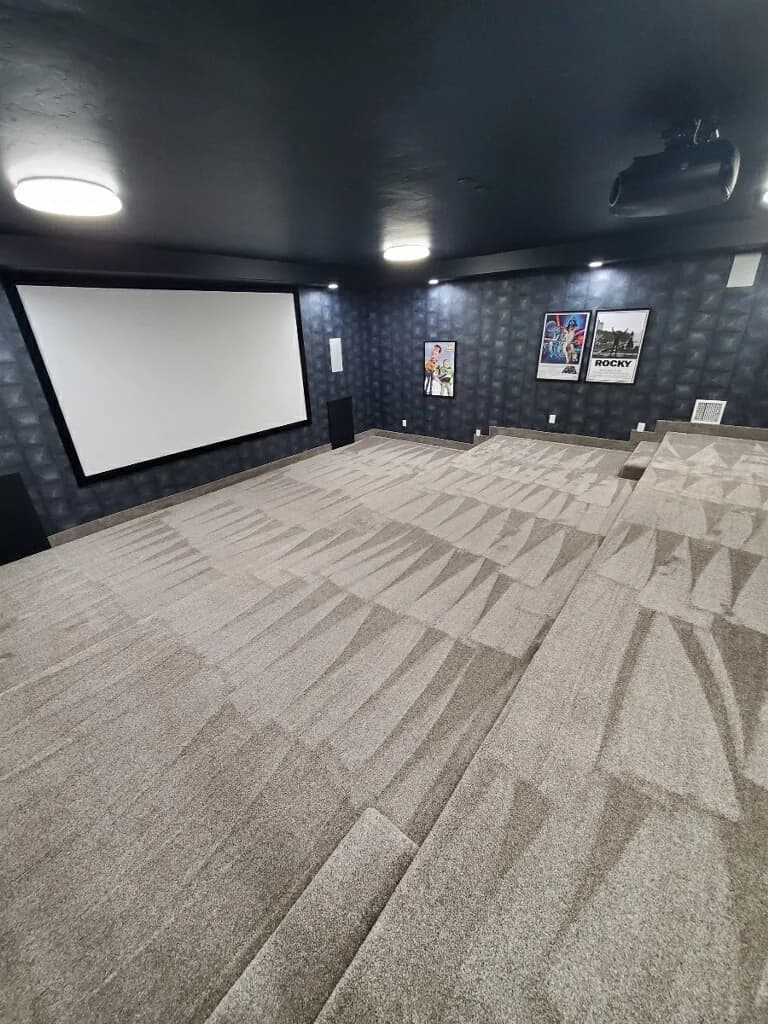 Finished basement home theater with tiered seating and projector screen