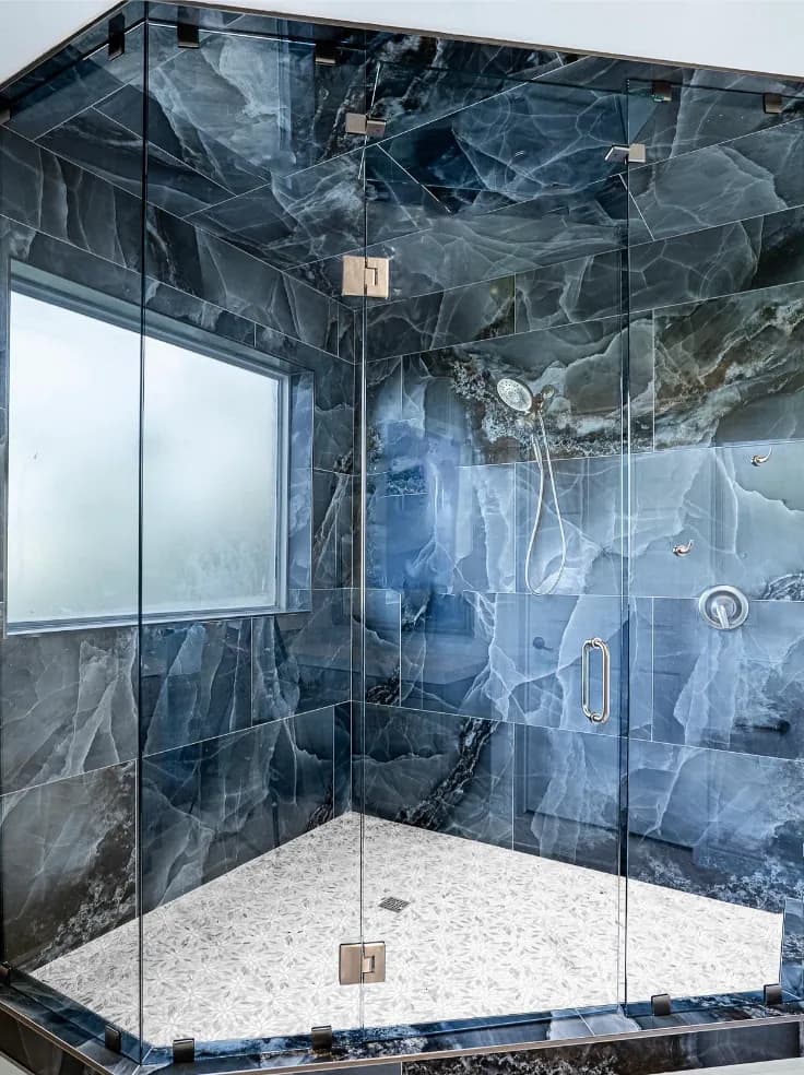Walk-in shower with blue onyx-look large-format tile, frameless glass, white hex mosaic floor