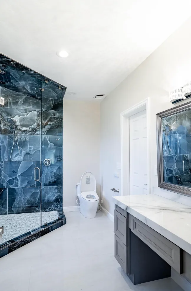 Blue onyx shower beside a vanity with makeup counter