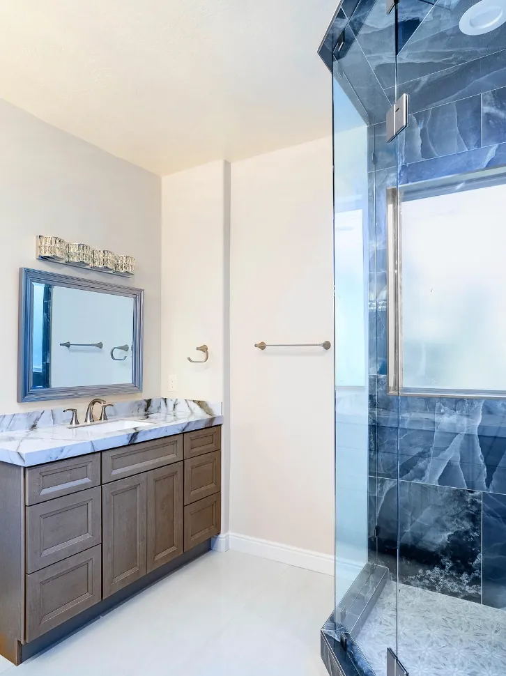 Dark-wood vanity with mirror, blue onyx shower glass in foreground