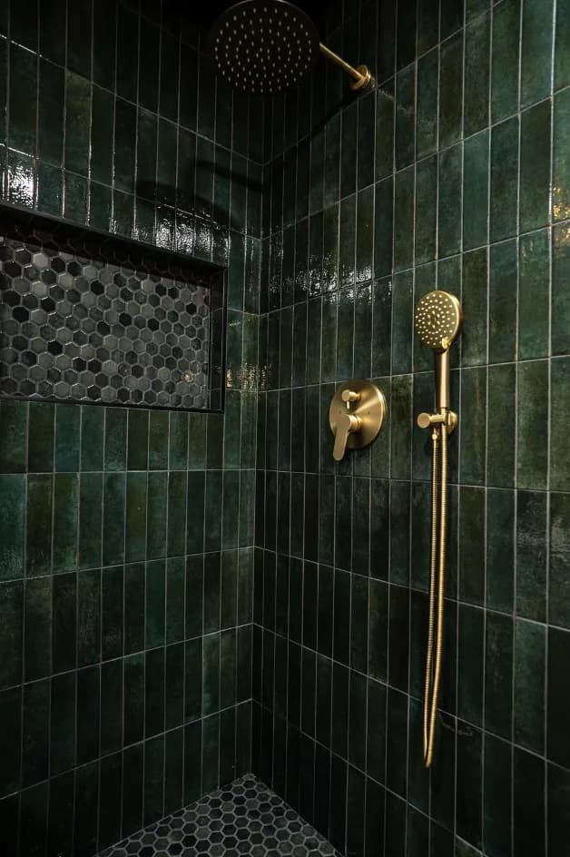 Walk-in shower with green vertical zellige-style tile, brass handheld and rain head, mosaic niche
