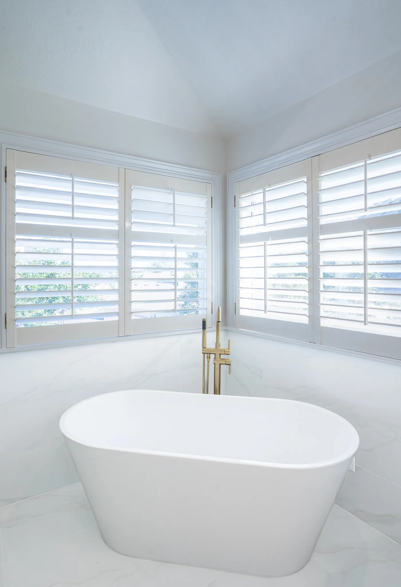 Glass shower with a bench and gold fixtures in a master bathroom remodel