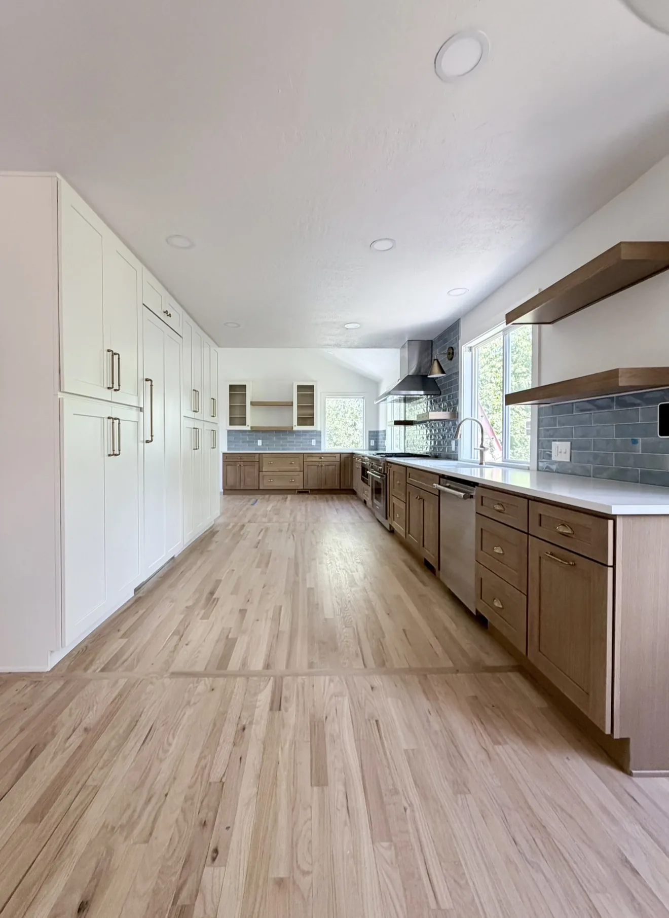 White pantry wall with open shelves, glass-front uppers, blue tile, and red oak floors