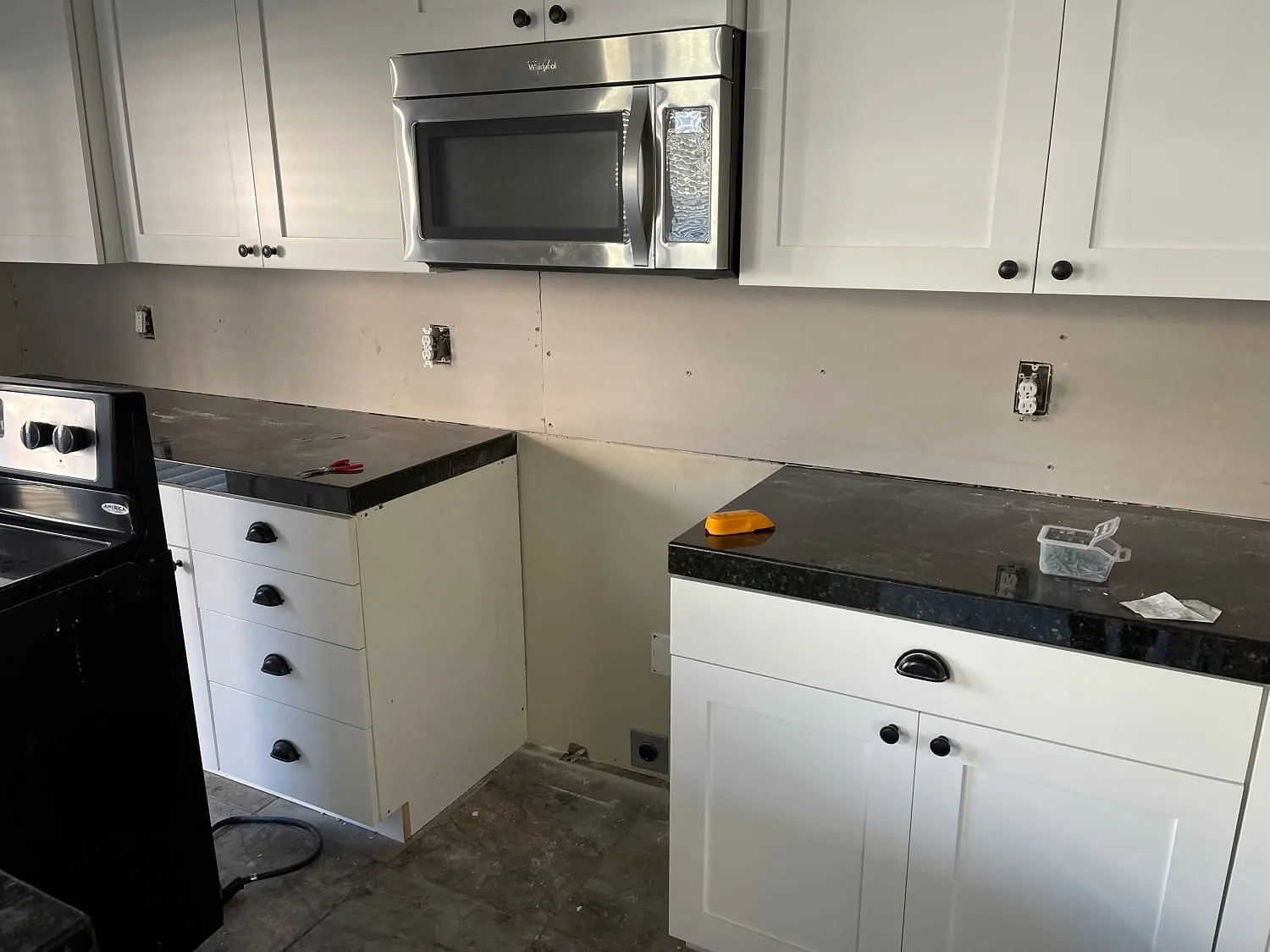 White shaker cabinets with black granite counters, backsplash not yet installed