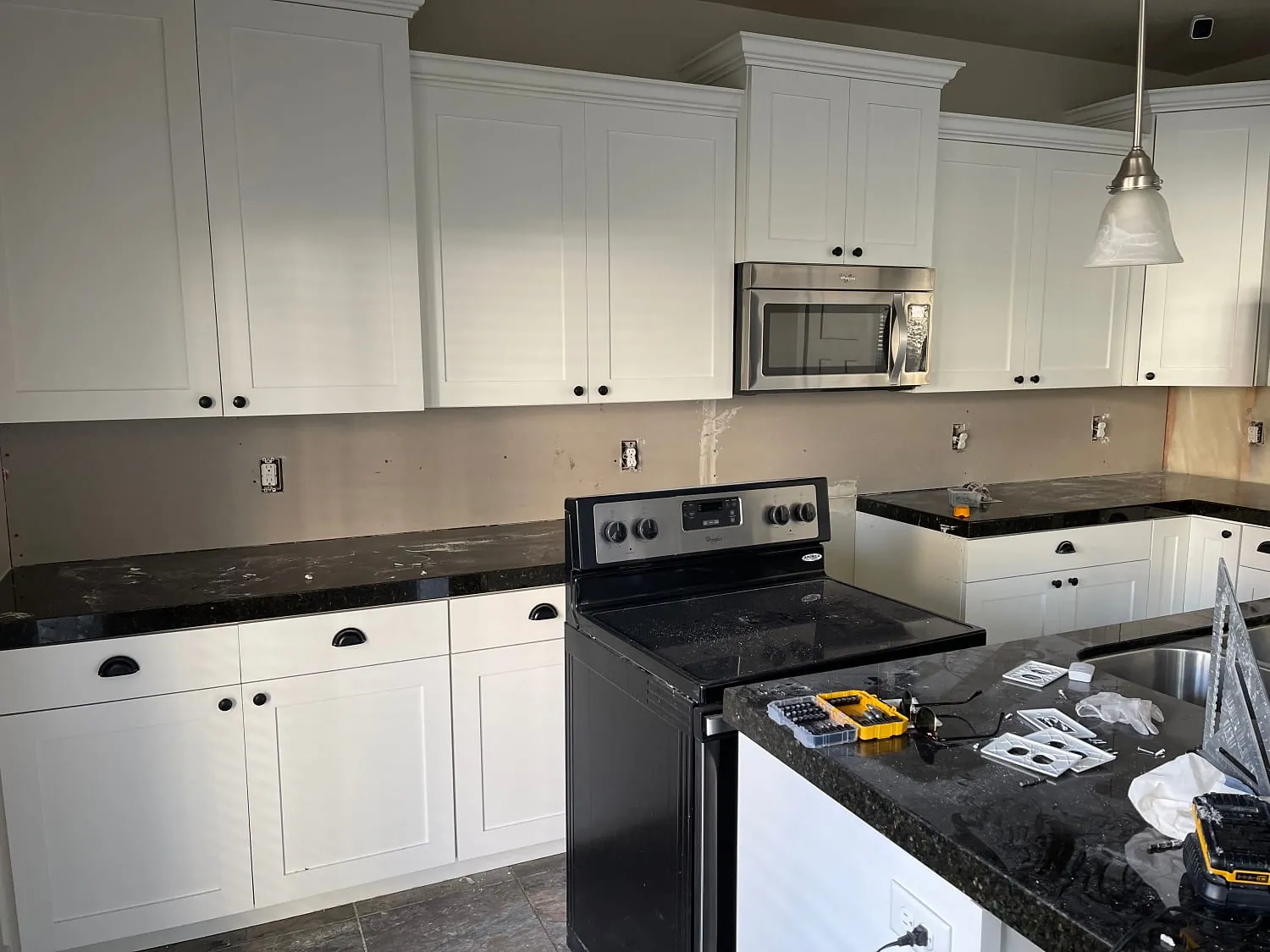Same kitchen, island with black granite top and range wall