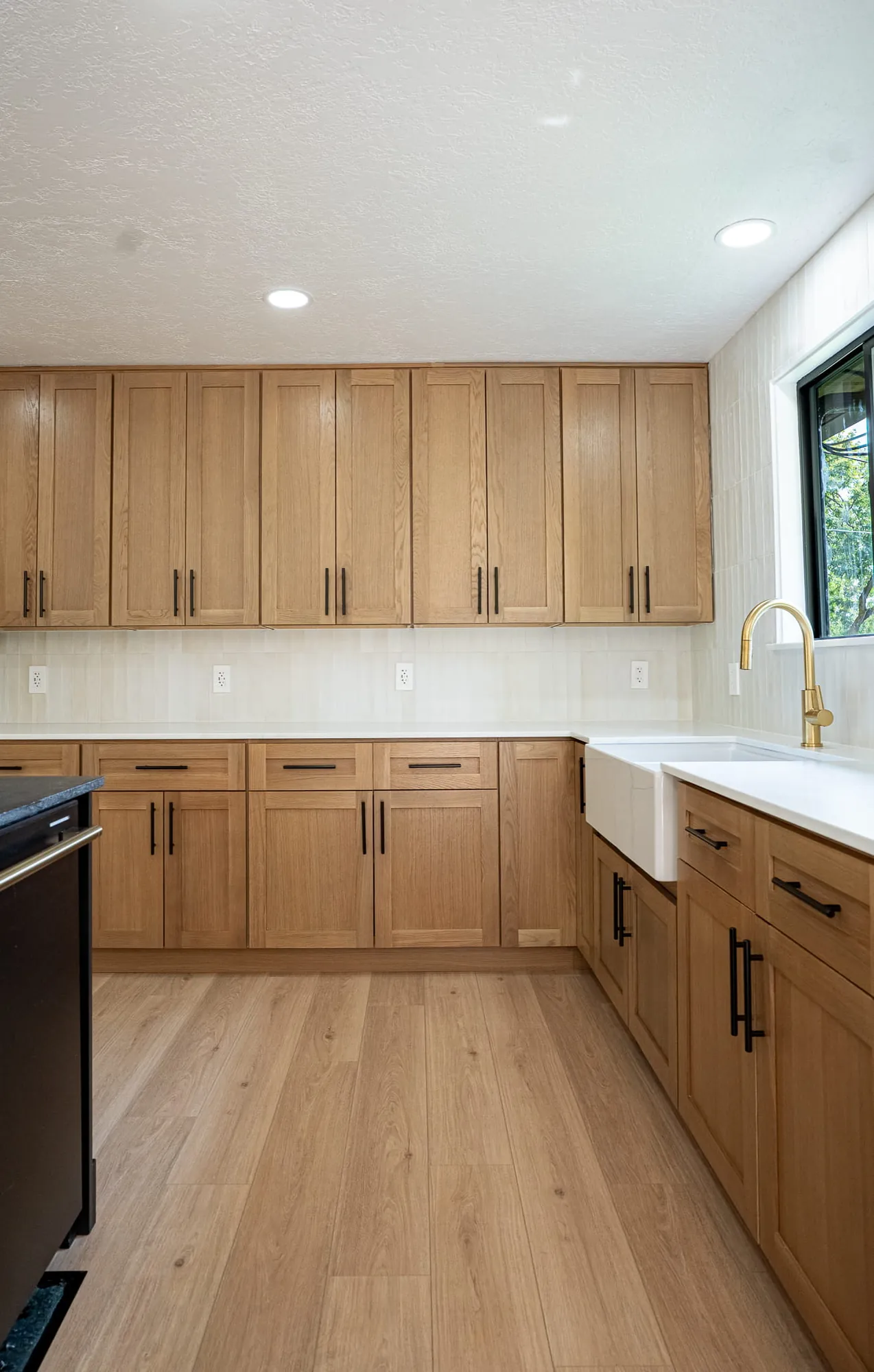 White-oak kitchen straight-on view, farmhouse sink and brass faucet