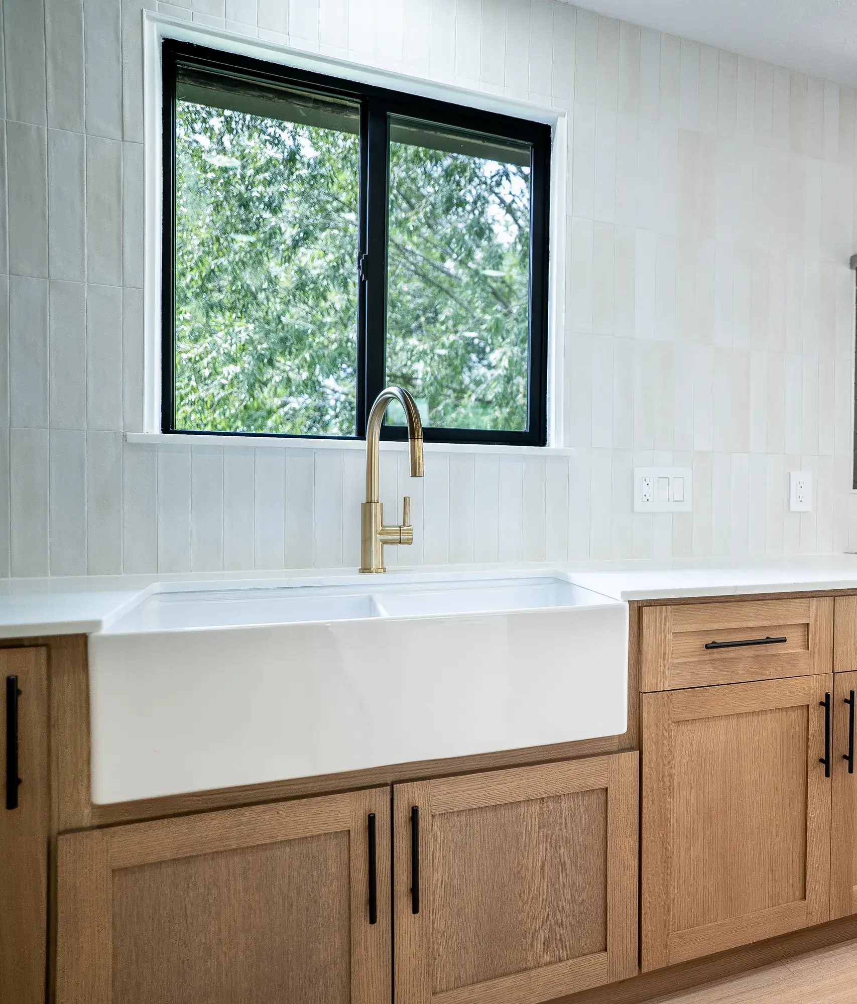 White oak fridge wall with black pulls and a paneled refrigerator