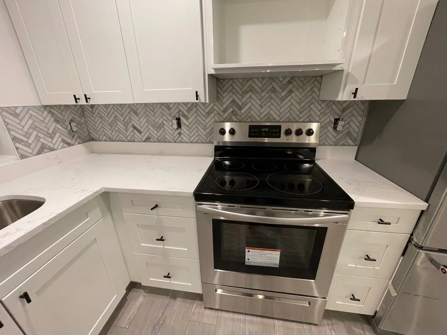 Same kitchen, corner range wall with herringbone backsplash