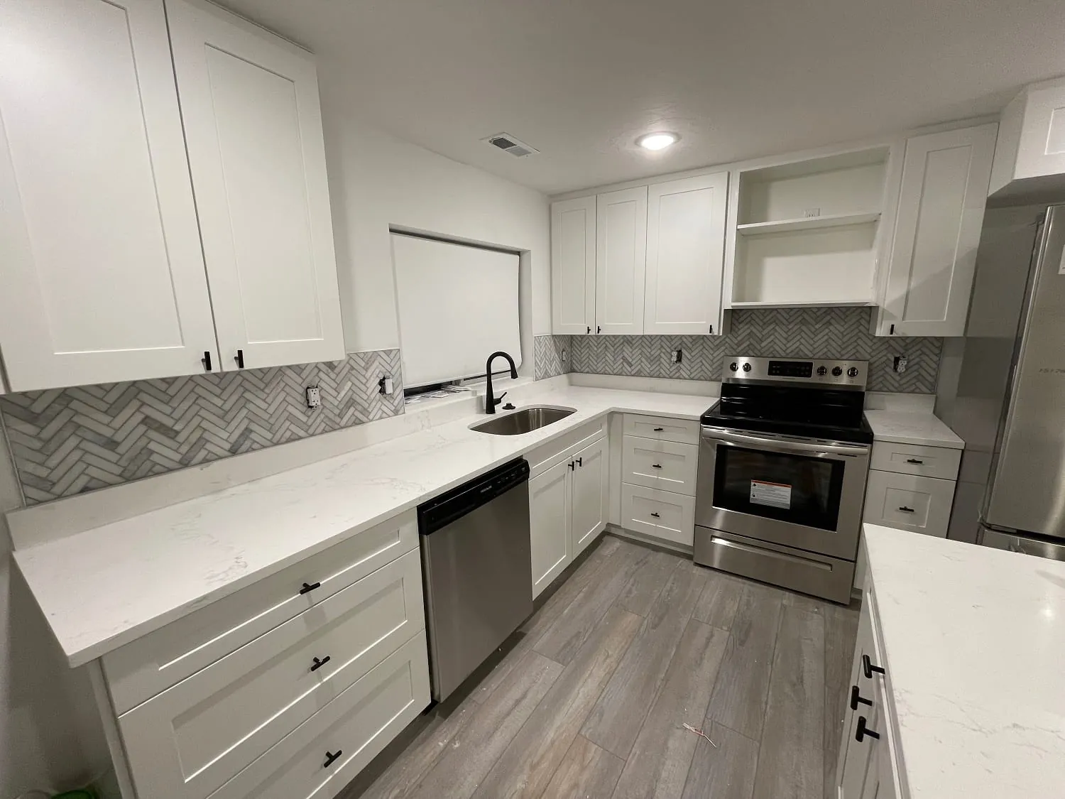 Same kitchen, wide view of sink run, dishwasher and range